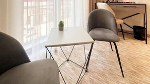 A modern hotel room with a large window, a desk, two chairs, and a small table. - North Star Hotel (Tashkent)