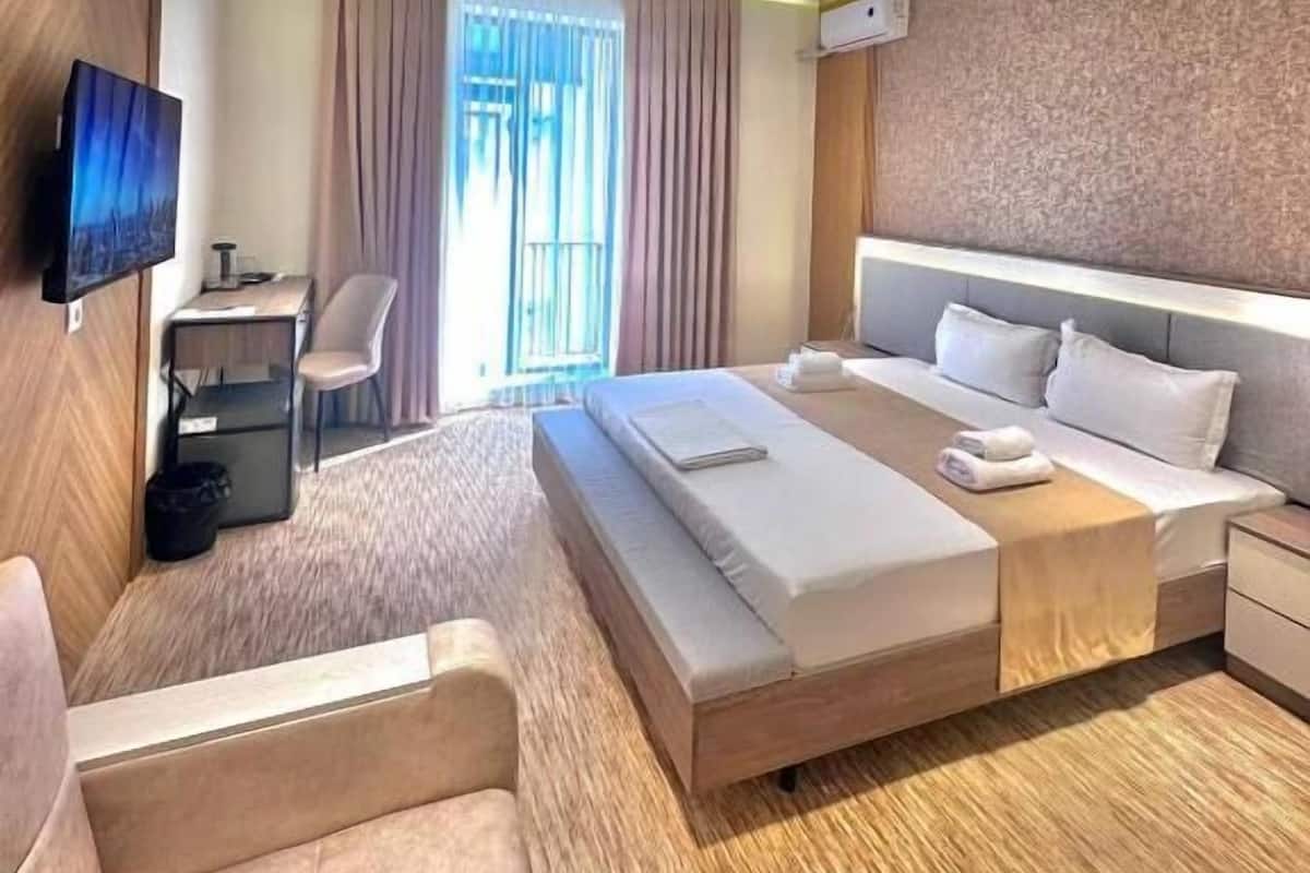Una habitación de hotel moderna con una cama grande, un escritorio, una silla y un televisor.