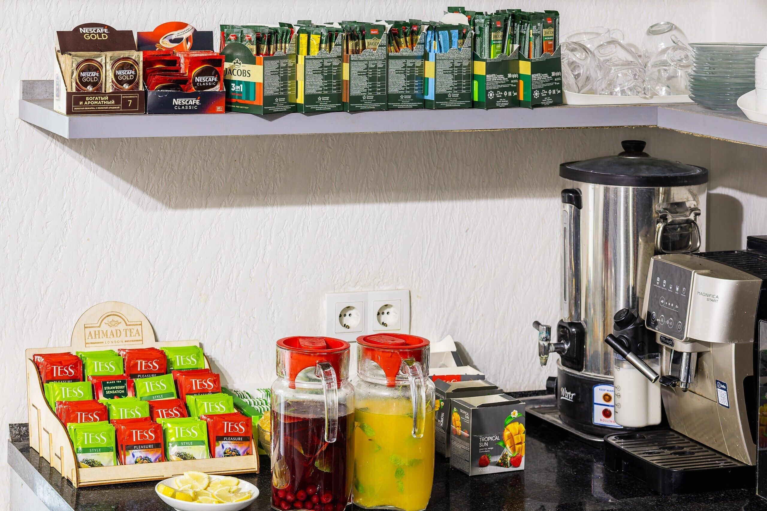 Un comptoir de cuisine avec une machine à café, des sachets de thé et différentes sortes de boîtes de thé.