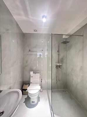 A modern bathroom with a glass-enclosed shower, a freestanding bathtub, and a toilet. - North Star Hotel (Tashkent)