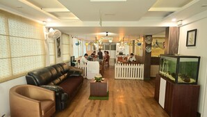 Un restaurante con piso de madera, asientos de cuero, valla de piquetes blancos y un acuario.