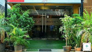 Entrada de hotel con puerta de cristal, rodeada de plantas en macetas.