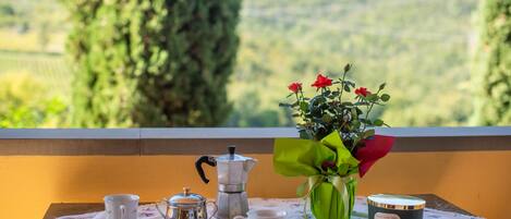 Ein Tisch mit einer Kaffeekanne, Tassen, einer Blumenvase und einer Kerze.