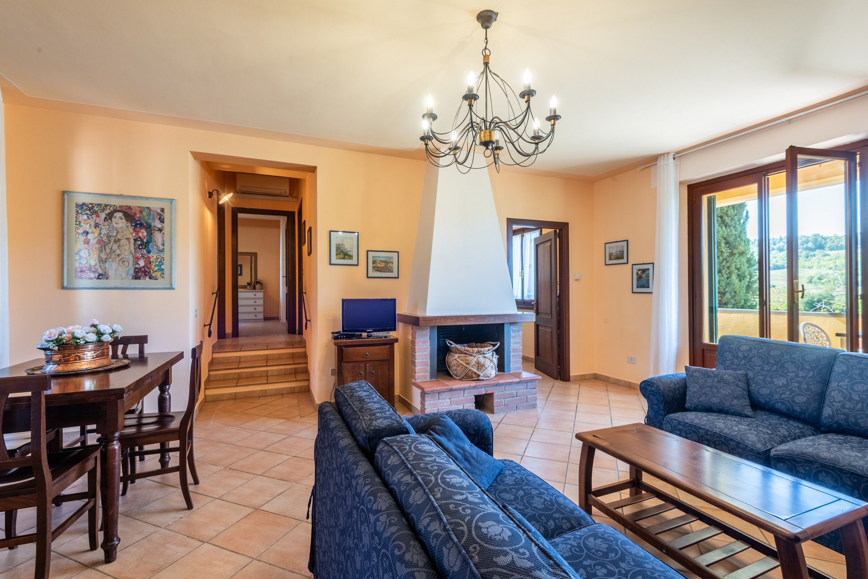 Uma sala de estar ampla com lareira, mesa de jantar com cadeiras, sofá e televisão.