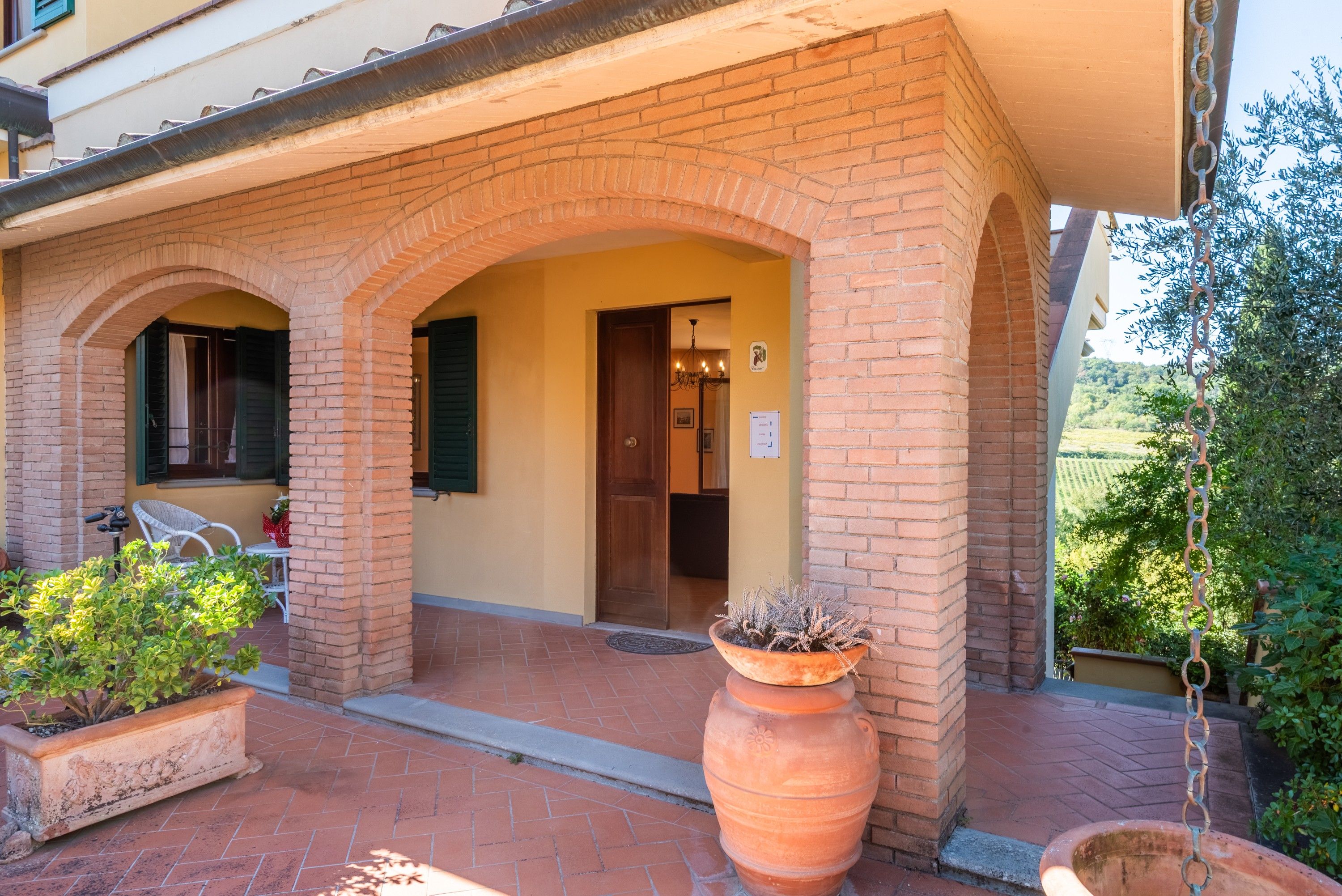 Un bâtiment avec une façade en briques, une entrée carrelée et un pot de fleurs en premier plan.