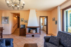 Un salon avec une cheminée, un canapé, un téléviseur et des œuvres d’art accrochées aux murs.