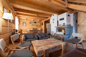 Ein gemütliches Holzinterieur mit Kamin aus Stein, bequemen Sitzmöglichkeiten und einem Essbereich.
