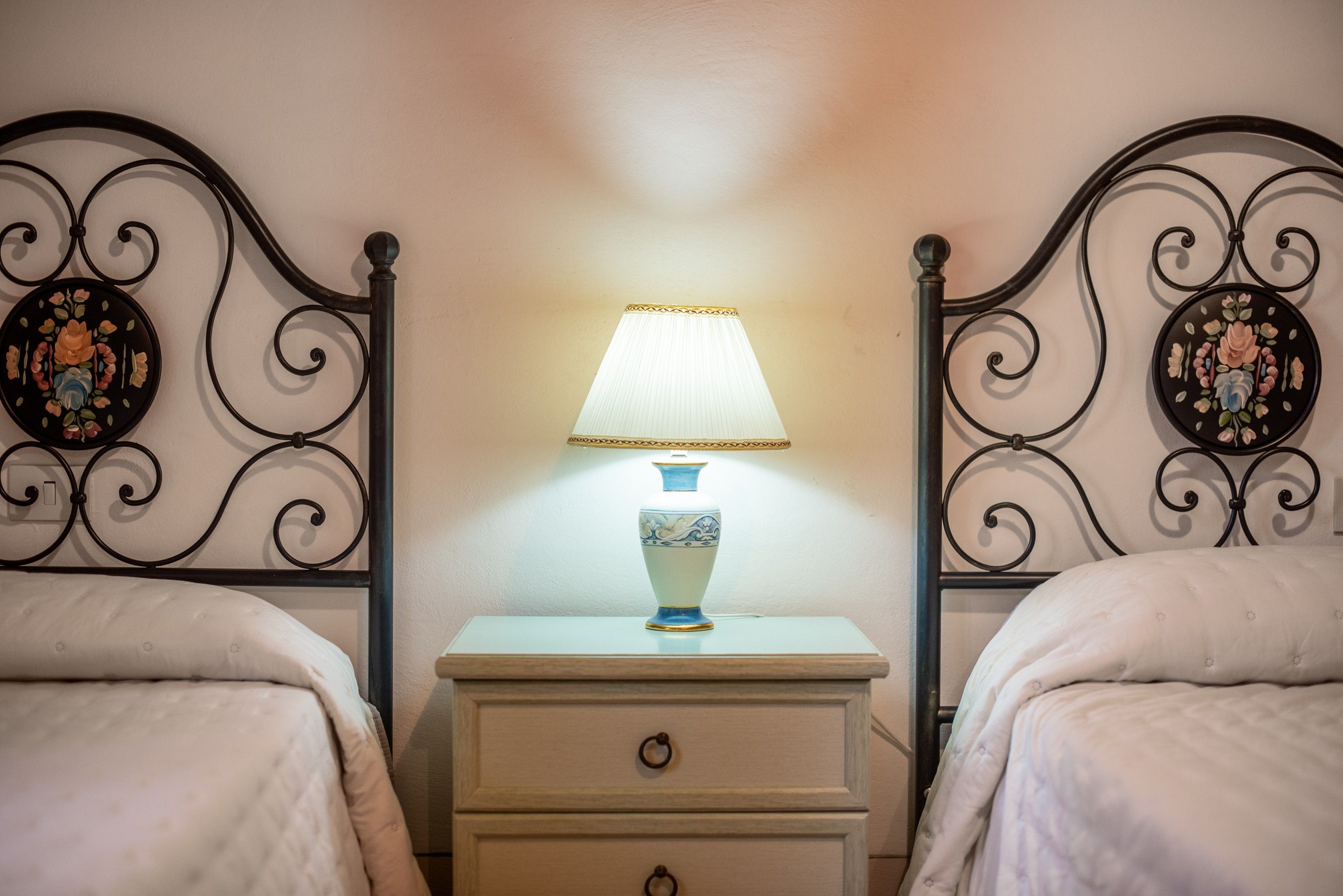 Una camera da letto con due letti, un comodino con una lampada e pannelli decorativi a parete.