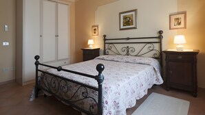 Un dormitorio con cama, armario, dos mesitas de noche con lámparas y un cuadro enmarcado en la pared.
