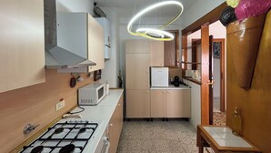 Een kleine keuken met een gasfornuis, magnetron en koelkast.