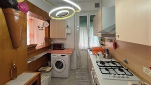 Een praktische keuken met een wasmachine, een gasfornuis en een magnetron.