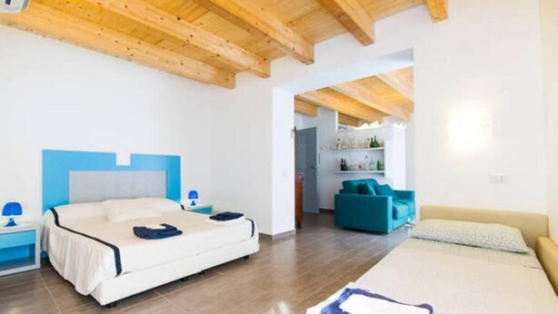 Un dormitorio con una cama, una mesita de noche, una silla azul y un sofá.
