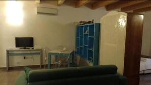 Una habitación con una cama, un escritorio con ordenador, una estantería azul y un sofá verde.