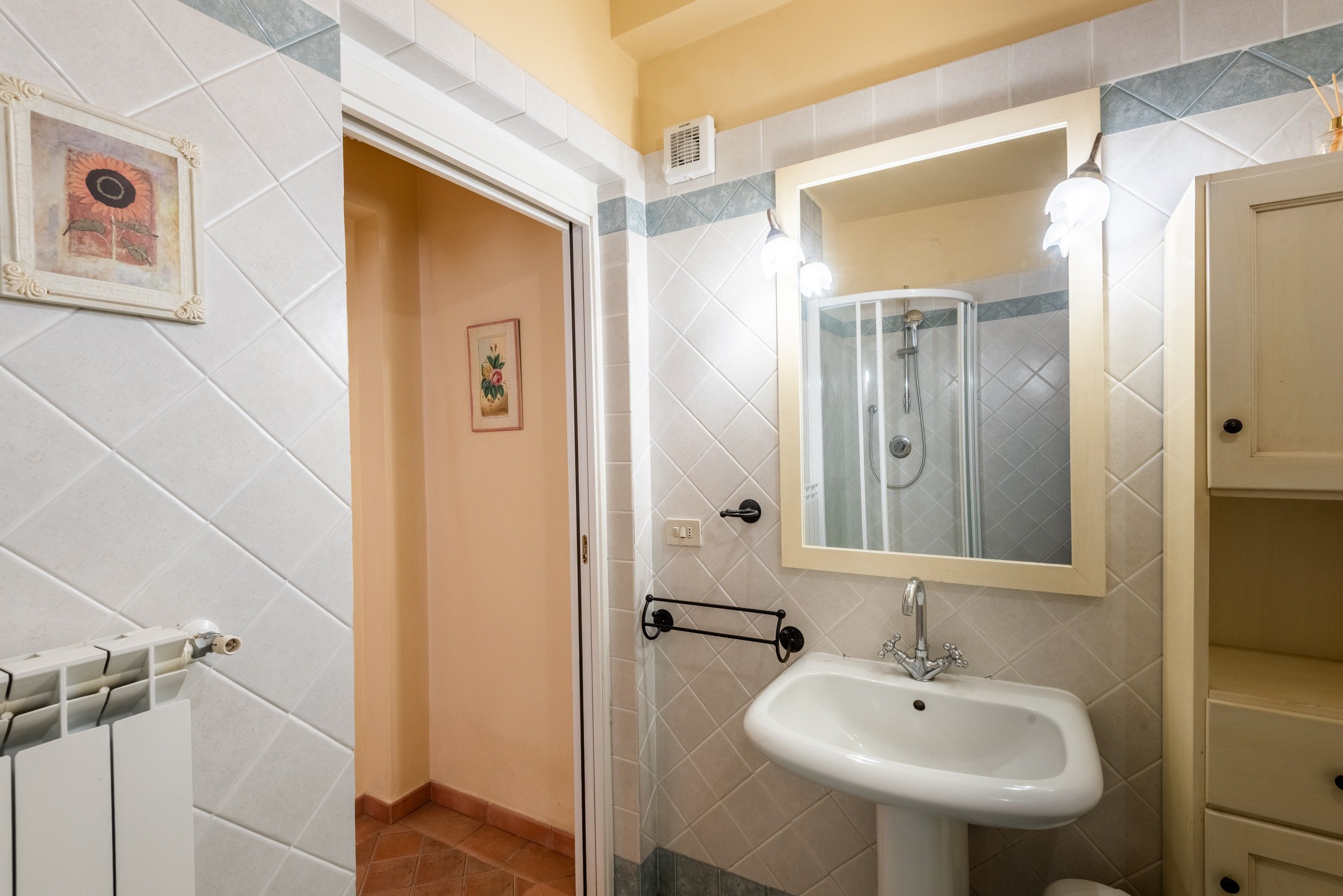 A bathroom with a white sink, a mirror, and a shower.
