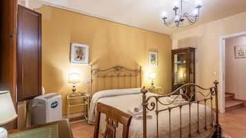A bedroom with a bed, bedside lamps, a heater, a mirror, and a chandelier.
