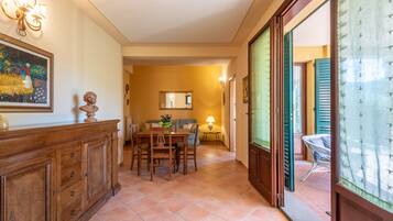 A dining area with a wooden table and chairs, a mirror on the wall, and a view through an open door.