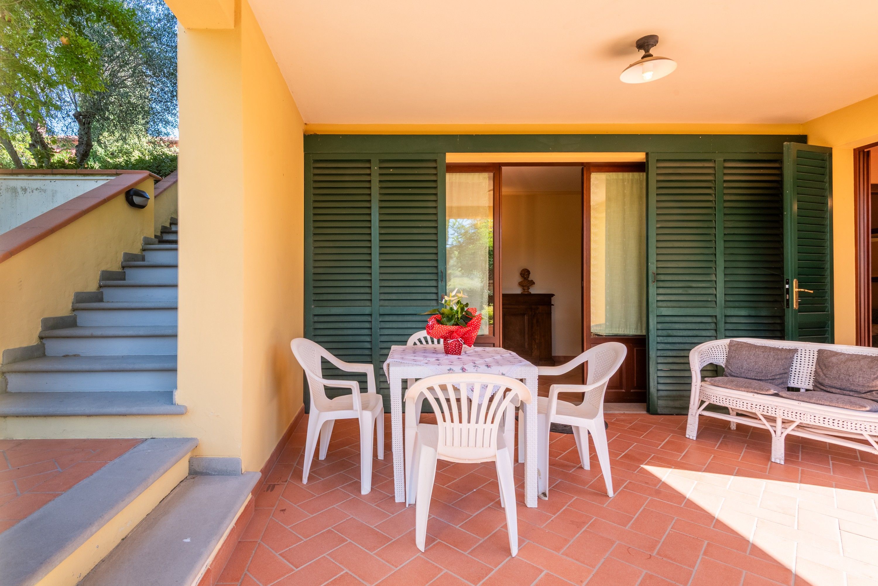 Un patio con tavolo e sedie, un divano e una scala che conduce a un livello superiore.