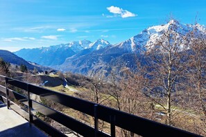 A mountain landscape with a clear sky, a road, and a railing.