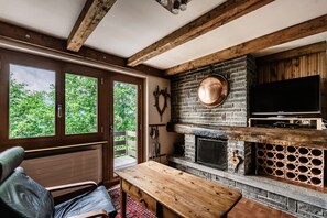 Una habitación con chimenea, televisión y ventana con vistas a follaje.