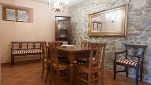 A dining area with a stone wall, wooden furniture, and a chandelier. - Agriturismo I Borghi – Apartment Liquirizia with Pool in San Gimignano (San Gimignano)