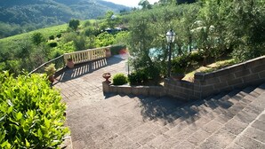 A paved outdoor area with steps leading to a terrace, surrounded by greenery and a view of a hilly landscape. - Agriturismo I Borghi – Apartment Liquirizia with Pool in San Gimignano (San Gimignano)