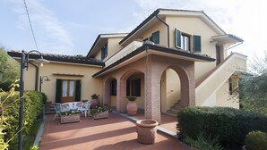 A two-story house with a patio, outdoor furniture, and potted plants. - Agriturismo I Borghi – Apartment Liquirizia with Pool in San Gimignano (San Gimignano)