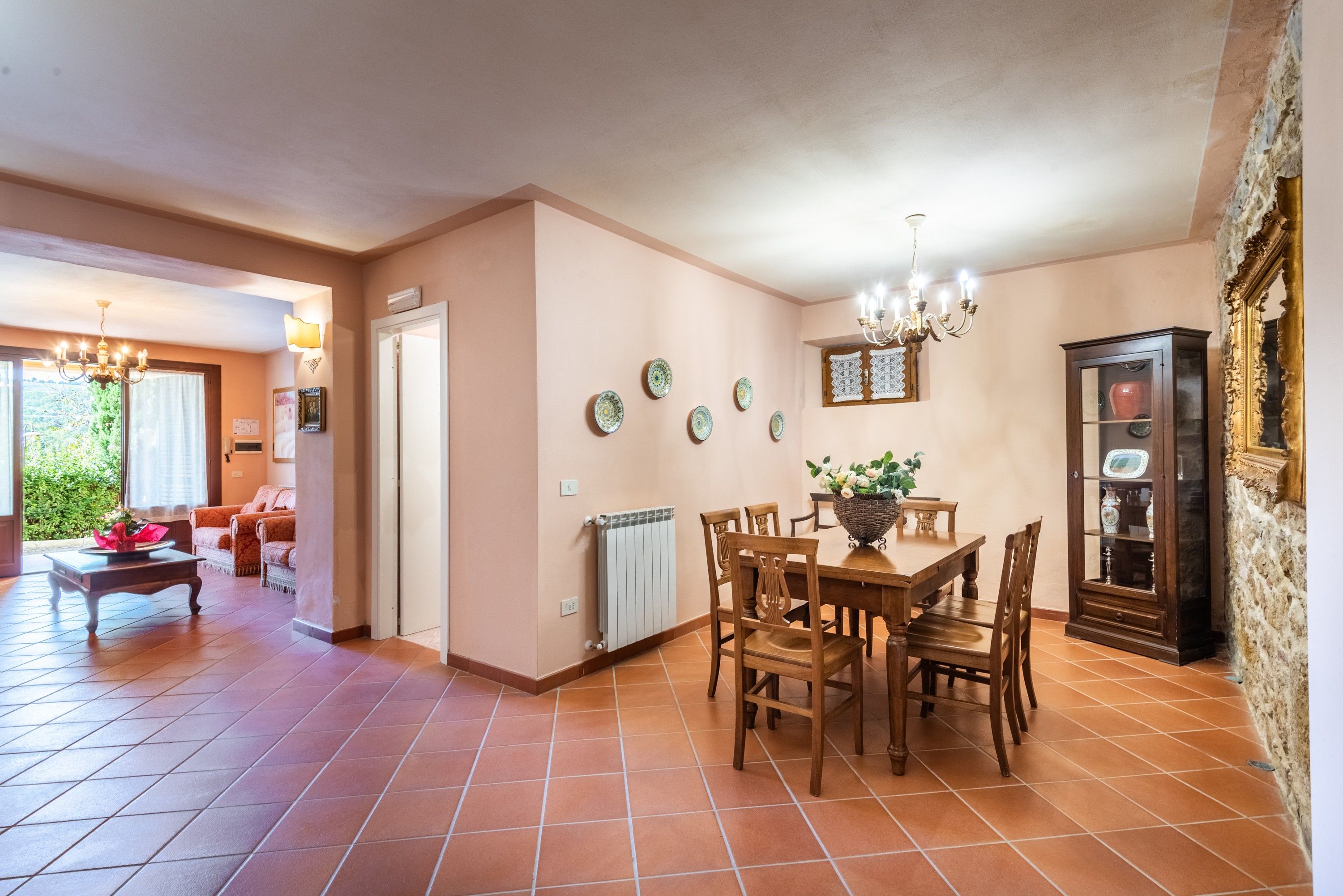A dining area with a wooden table and chairs, a radiator, and a cabinet with glass doors.