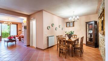 A dining area with a wooden table and chairs, a radiator, and a cabinet with glass doors.