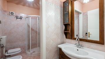 Ein Badezimmer mit Dusche, Toilette, Waschbecken und Spiegel.