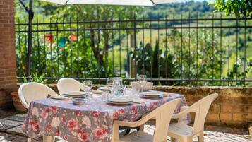 An outdoor dining area with a table set for four, surrounded by chairs, under a canopy.