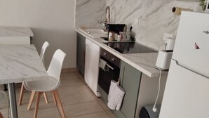 A modern kitchen with a marble countertop, white chairs, a built-in oven, and a refrigerator. - Relaxing vacations (Canet-en-Roussillon)
