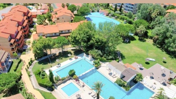 A resort with multiple swimming pools, lush greenery, and residential buildings with red-tiled roofs. - Relaxing vacations (Canet-en-Roussillon)