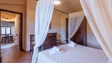 Ein Schlafzimmer mit einem Himmelbett, einem Holzkopfstück und einem großen Fenster mit Vorhängen.