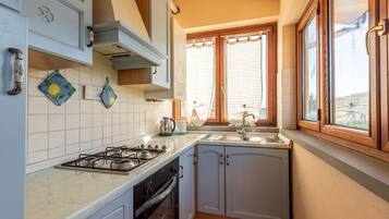 Una cucina con piano cottura a gas, forno e una finestra con tende.