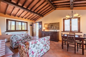 Un salon spacieux avec un haut plafond, une cheminée et un coin repas agrémenté de meubles en bois.