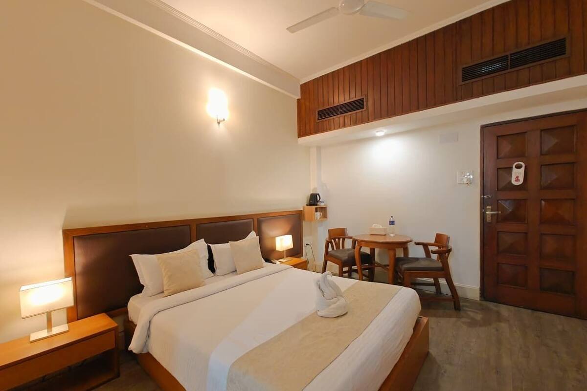 A hotel room with a bed, bedside tables, a desk, and a chair.