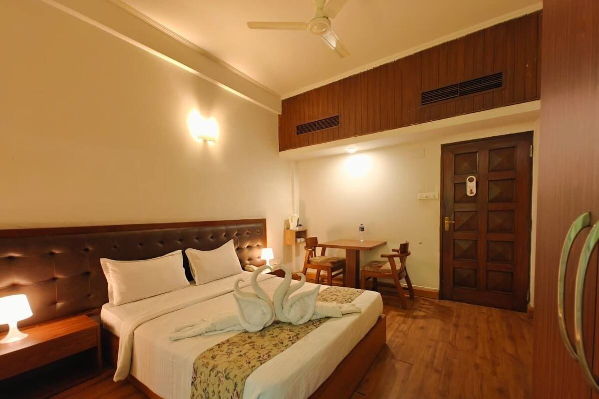 A hotel room with a large bed, a wooden headboard, a desk with a chair, and a door with a handle.