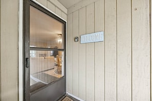 Eine Tür mit einem 'WELCOME'-Schild, einer Glasscheibe und einer Holzwand.