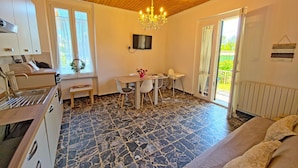 Una habitación con techo de madera, un comedor con mesa y sillas, una cocina con fregadero y un ventanal grande.