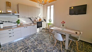 Una cocina moderna con armarios blancos, encimera de mármol, horno integrado y un comedor con mesa y sillas.