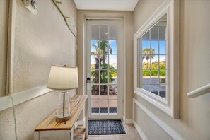 A hallway with a door, a lamp, and a window. - Sunrise Waterfront 2BR Townhome - Pool Private Terraces (Ruskin)