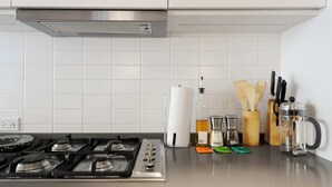 A kitchen with a gas stove, white tiled backsplash, and various kitchen utensils and appliances. - w Amazing 2BR in Roma Norte (Mexico City)