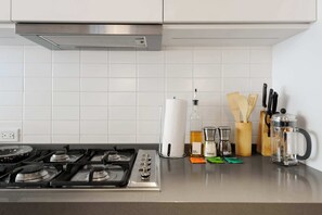 A kitchen with a gas stove, white tiled backsplash, and various kitchen utensils and appliances. - w Amazing 2BR in Roma Norte (Mexico City)