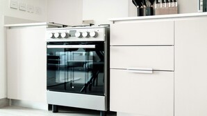 Una cocina moderna con horno de acero inoxidable, armarios blancos y una encimera con utensilios de cocina.