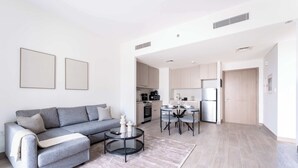 Una sala de estar moderna con un sofá gris, una mesa de centro y una zona de comedor con una mesa pequeña y sillas.