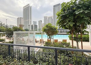 Área da piscina com espreguiçadeiras e vista para edifícios altos.