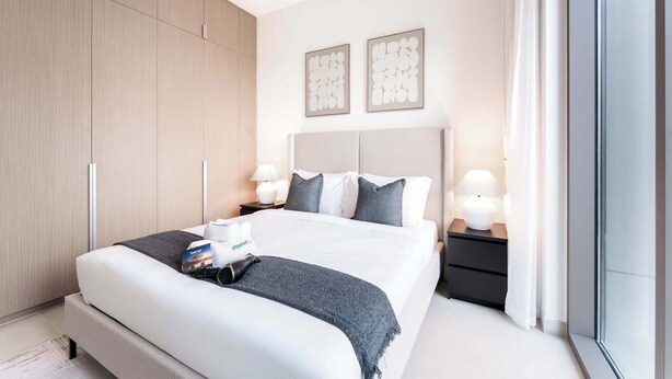 Una habitación de hotel moderna con una cama grande, mesitas de noche y un armario.