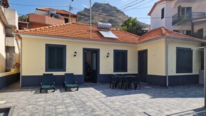 Ein Gebäude mit einem Ziegeldach, einer Terrasse mit Sitzgelegenheiten und einer Tür zum Eingang.