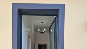 Ein Flur mit Holzboden, der zu einem Raum mit einer dunkelblauen Tür und einer weißen Wand führt.