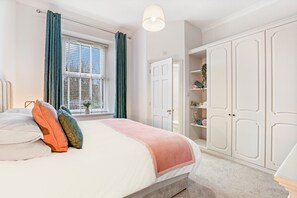 A bedroom with a bed, a window with curtains, a wardrobe, and a bedside table. - Church View - North East Escapes (Lanchester)